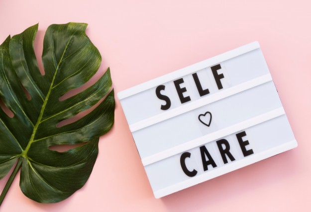 Image promoting self care for counsellors. Cheeseplant leaf and self care sign against a pink background